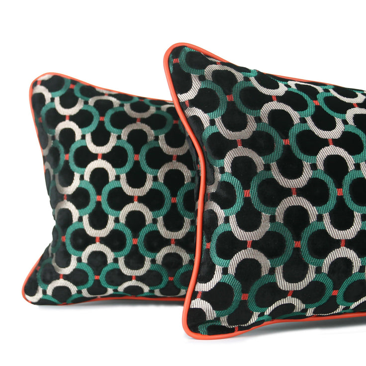 Detailed close up of black velvet decorative lumbar pillows with emerald green and silver geometric pattern and bright orange leather contrast welt. Hand-sewn in Charlotte NC by Liz Saintsing.